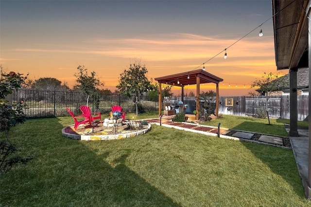 yard at dusk with a fenced backyard, a water view, and a fire pit