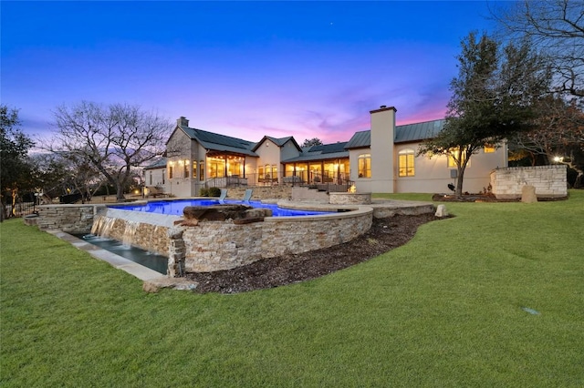 pool at dusk featuring a yard and an outdoor pool