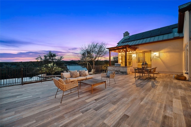 deck at dusk with outdoor dining area, outdoor lounge area, and a pergola