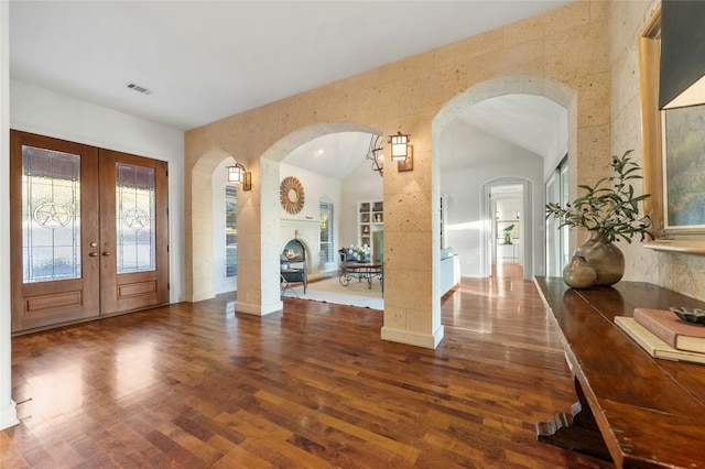 1386 Patterson Rd, Austin, TX 78733 - foyer entrance with wood finished floors, arched walkways, french doors, high vaulted ceiling, and a warm lit fireplace