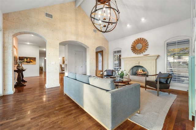 living area with a warm lit fireplace, visible vents, arched walkways, dark wood-type flooring, and high vaulted ceiling