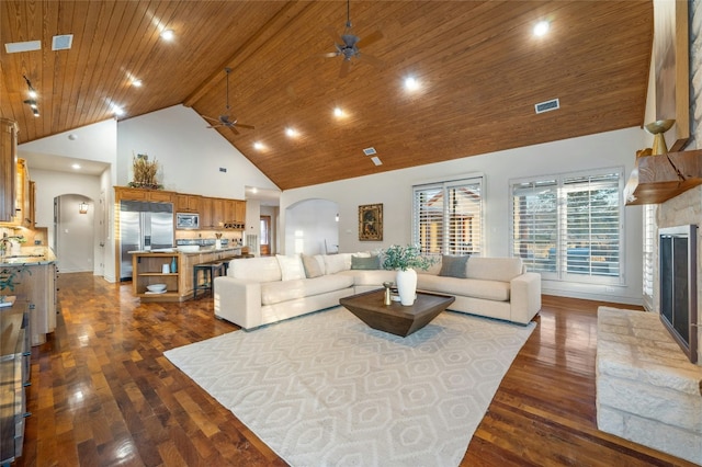 living area featuring arched walkways, a fireplace with raised hearth, visible vents, high vaulted ceiling, and wooden ceiling