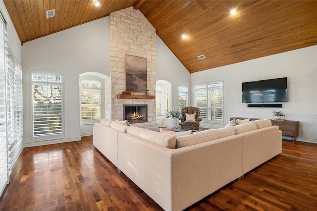 living area with high vaulted ceiling, a stone fireplace, wooden ceiling, dark wood-style flooring, and plenty of natural light