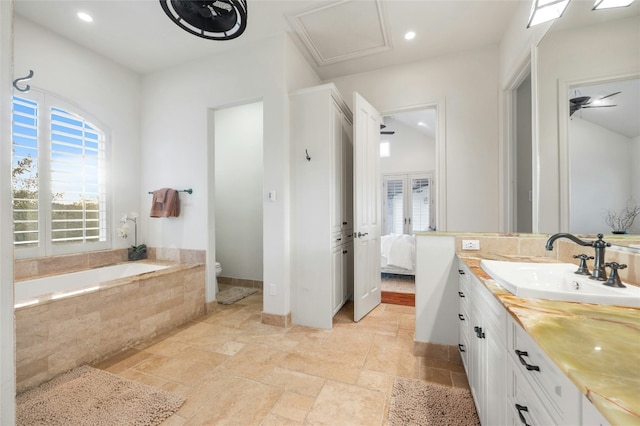 ensuite bathroom featuring toilet, ensuite bath, stone finish floor, a garden tub, and vanity