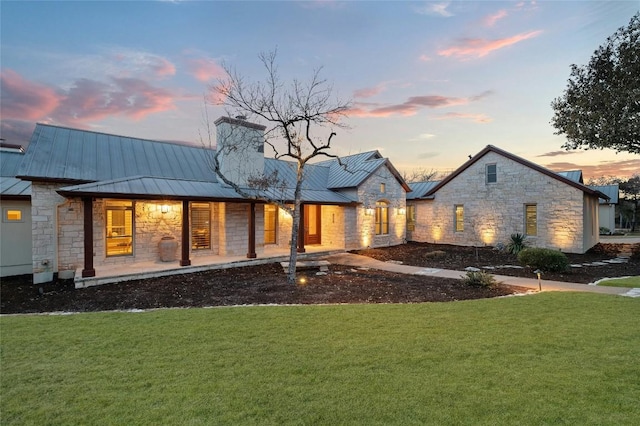 1386 Patterson Rd, Austin, TX 78733 - back of house with stone siding, a standing seam roof, a yard, and a chimney