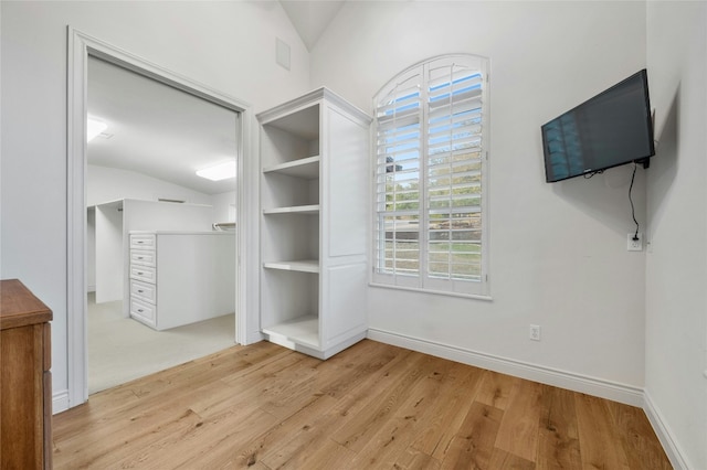 interior space with vaulted ceiling, light wood finished floors, and baseboards