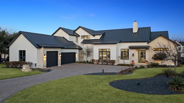 modern farmhouse with metal roof, stone siding, decorative driveway, a standing seam roof, and a front yard