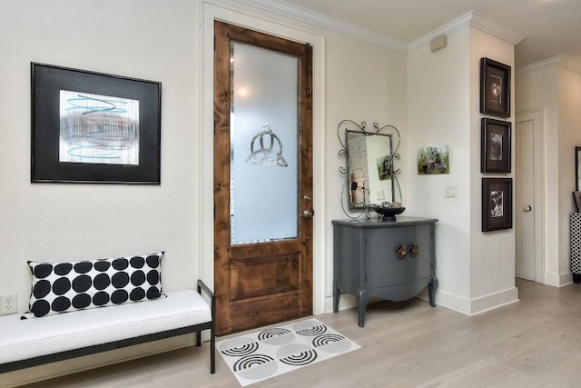 entrance foyer with ornamental molding, light wood-type flooring, and baseboards