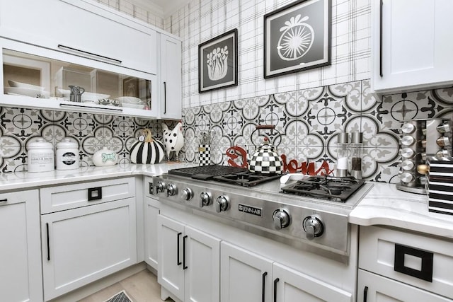 kitchen featuring glass insert cabinets, stainless steel gas cooktop, white cabinetry, and decorative backsplash