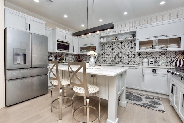 kitchen featuring stainless steel appliances, a breakfast bar, white cabinetry, light stone countertops, and open shelves