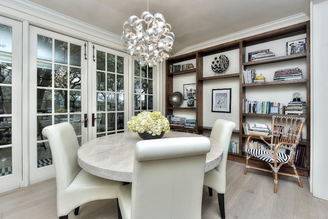 dining space with ornamental molding, light wood-type flooring, and a notable chandelier