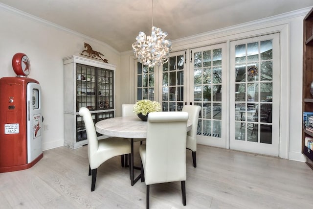 dining area featuring light wood finished floors, baseboards, ornamental molding, and a notable chandelier