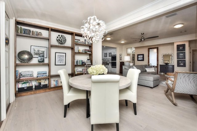 dining room featuring light wood-style floors, ornamental molding, and ceiling fan with notable chandelier