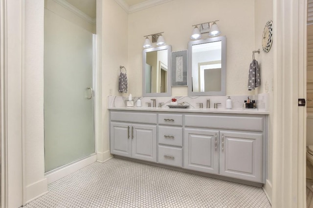 bathroom featuring toilet, baseboards, double vanity, a stall shower, and crown molding