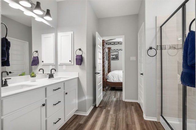 full bathroom with double vanity, a sink, ensuite bath, and wood finished floors