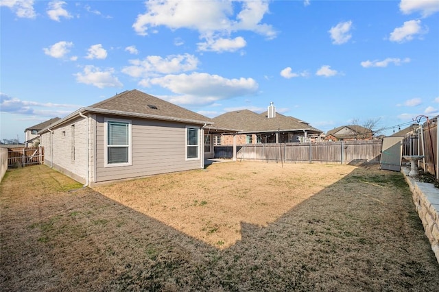 rear view of property featuring a lawn and a fenced backyard