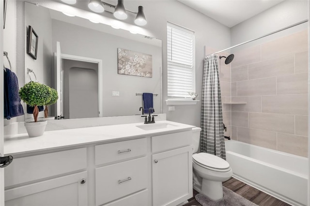 bathroom with toilet, wood finished floors, visible vents, vanity, and shower / tub combo with curtain