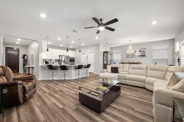 living area featuring arched walkways, ceiling fan, recessed lighting, wood finished floors, and visible vents