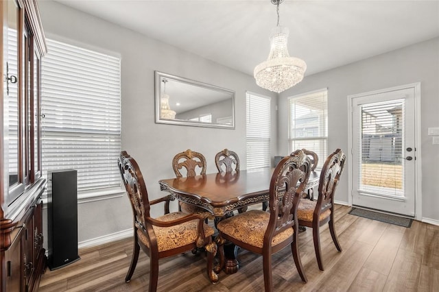 dining space featuring a chandelier, wood finished floors, and baseboards