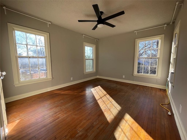 empty room featuring dark wood-style floors, a ceiling fan, baseboards, and a textured ceiling