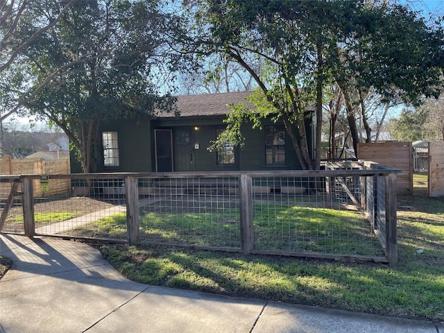 view of front facade featuring roof with shingles, a fenced front yard, and a gate