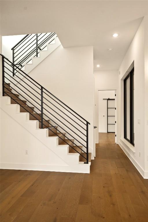 staircase featuring baseboards, wood finished floors, and recessed lighting