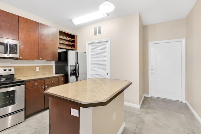 2505 San Gabriel St Unit 212, Austin, TX 78705 - kitchen featuring appliances with stainless steel finishes, open shelves, light tile patterned floors, and baseboards