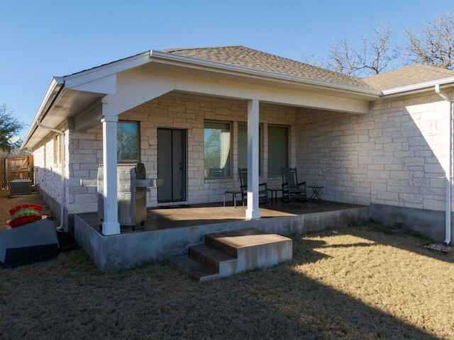 exterior space featuring stone siding, a shingled roof, and central AC