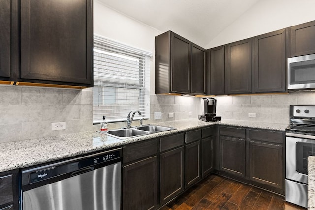 kitchen with tasteful backsplash, lofted ceiling, dark wood-type flooring, stainless steel appliances, and a sink