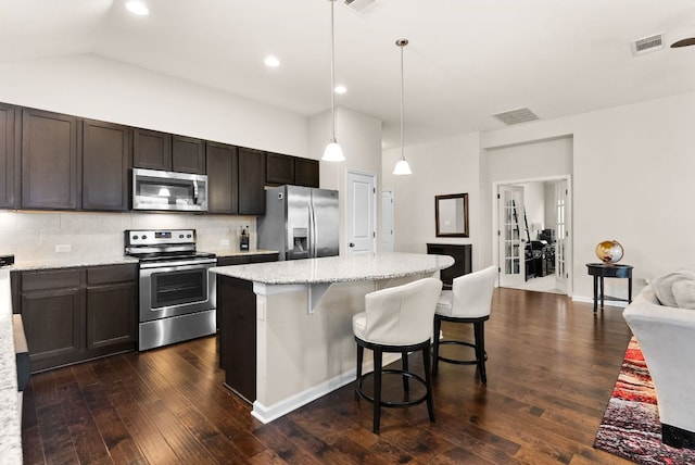 kitchen featuring light stone counters, a center island, visible vents, hanging light fixtures, and appliances with stainless steel finishes