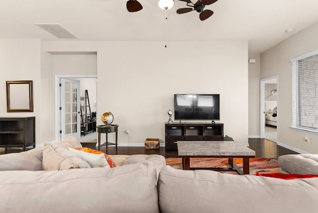 living area featuring dark wood-style floors, baseboards, visible vents, and ceiling fan