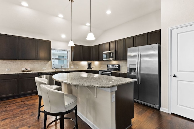 kitchen featuring a center island, dark wood-style flooring, a breakfast bar area, stainless steel appliances, and hanging light fixtures