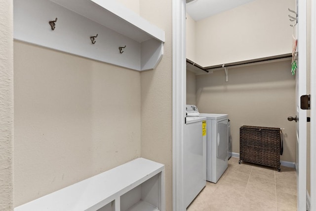 washroom featuring washing machine and dryer, laundry area, baseboards, and light tile patterned floors