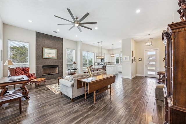 living room featuring visible vents, a fireplace, baseboards, and dark wood-style flooring