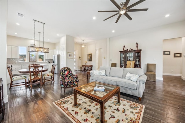 living room featuring a ceiling fan, visible vents, baseboards, dark wood-style flooring, and recessed lighting