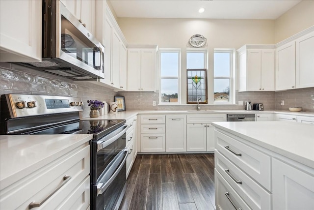kitchen featuring a sink, stainless steel appliances, white cabinets, dark wood finished floors, and recessed lighting