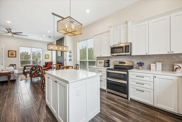 kitchen featuring a kitchen island, stainless steel appliances, open floor plan, and plenty of natural light