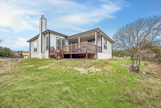 rear view of property featuring a deck, a chimney, and a lawn