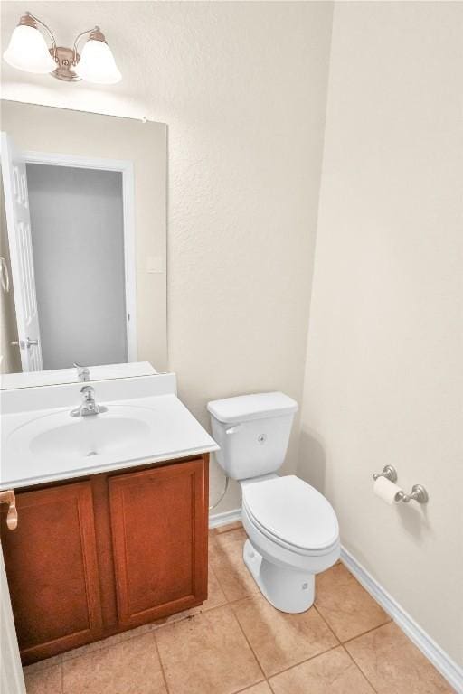 half bath featuring baseboards, vanity, toilet, and tile patterned floors