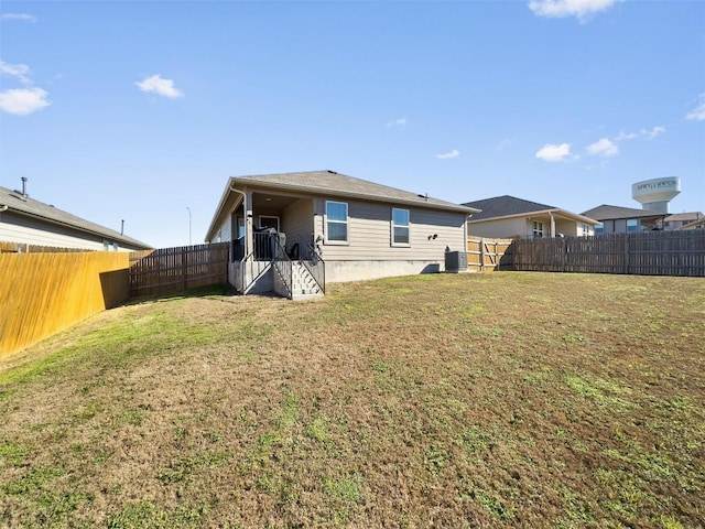 back of property featuring a fenced backyard, central AC, and a yard