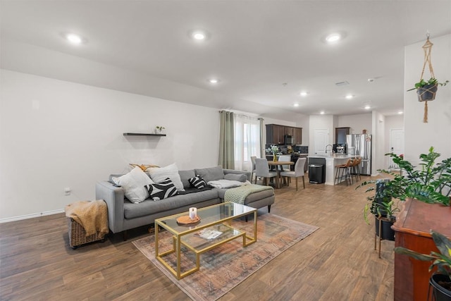 living room with baseboards, dark wood finished floors, and recessed lighting