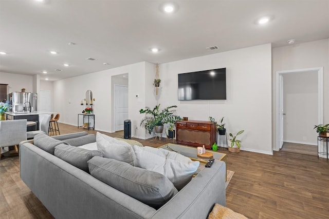 living room featuring dark wood-style floors, baseboards, visible vents, and recessed lighting