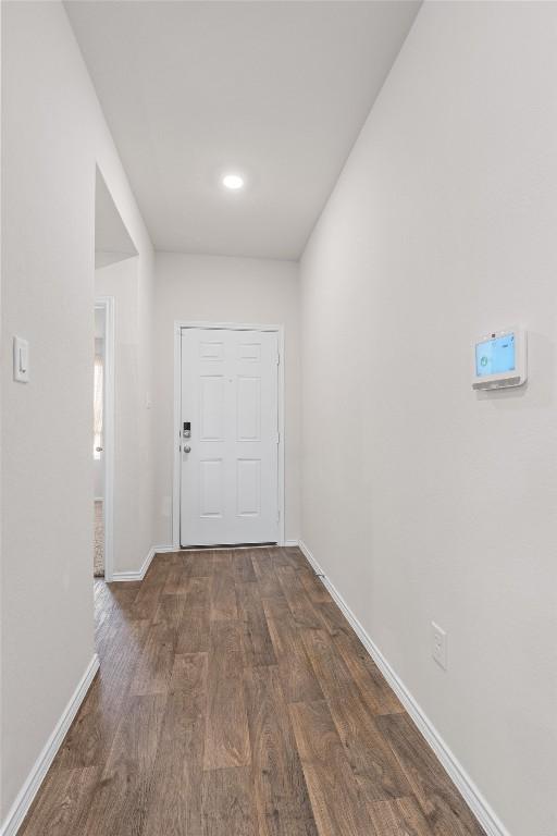 corridor with baseboards and dark wood finished floors