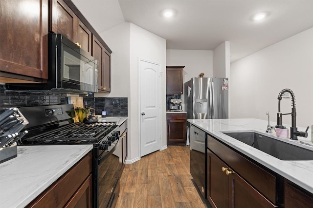 kitchen featuring light stone counters, dark wood-type flooring, a sink, and black appliances