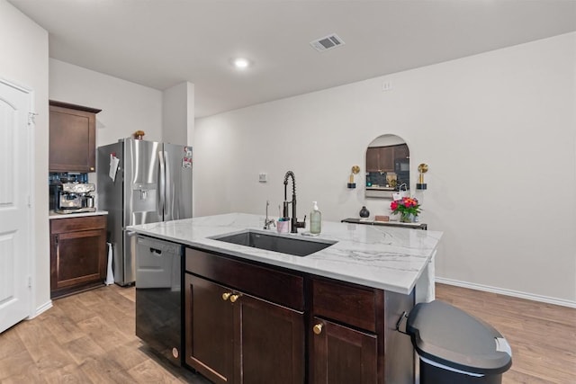 kitchen with visible vents, dishwasher, light wood-style flooring, a kitchen island with sink, and a sink