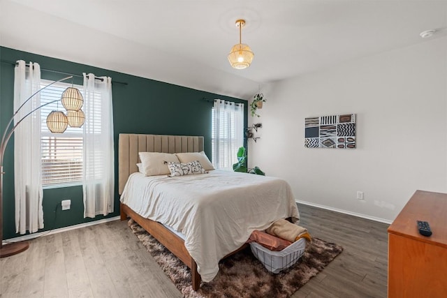 bedroom featuring baseboards, vaulted ceiling, and wood finished floors