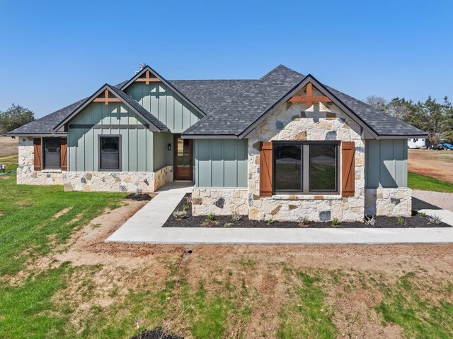 1730 County Road 217, Giddings, TX 78942 - modern farmhouse with stone siding, board and batten siding, a front lawn, and a shingled roof