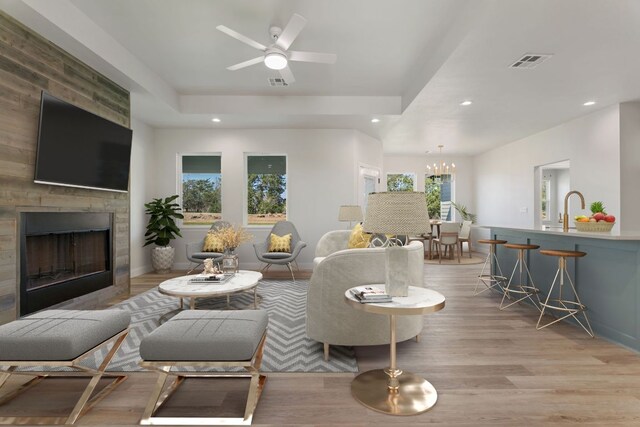 living room featuring light wood-type flooring, a raised ceiling, visible vents, and recessed lighting