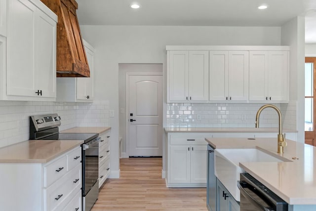 kitchen featuring dishwashing machine, white cabinets, stainless steel range with electric cooktop, light countertops, and light wood finished floors