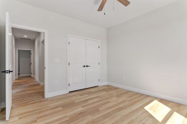 unfurnished bedroom featuring visible vents, a closet, light wood-style flooring, and baseboards